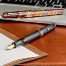 Leonardo Fountain Pen - Momento Magico (14K Gold) - Millefiori - New Edition (2022) - Pens and Laptop on a Brown Background