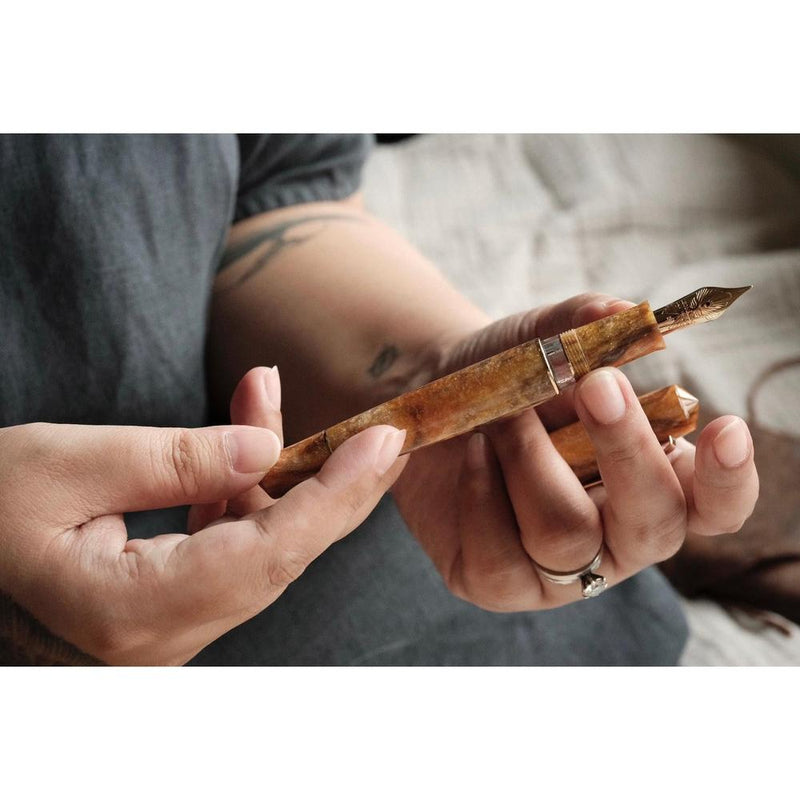 Leonardo × @twenty_sides Momento Zero Grande 2.0 Midas Fountain Pen - Pen Being Held By Two Hands Of A Person | EndlessPens