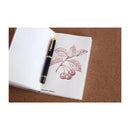 Pennonia Meggyes Sour Cherry Ink Bottle (60ml) - A Fountain Pen On Top Of A Notebook With An Ink Drawing