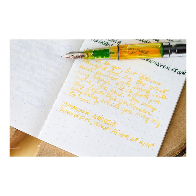 Pennonia Napkelte Sunrise Ink Bottle (60ml) - A Fountain Pen On Top Of A Notebook With An Ink Writing