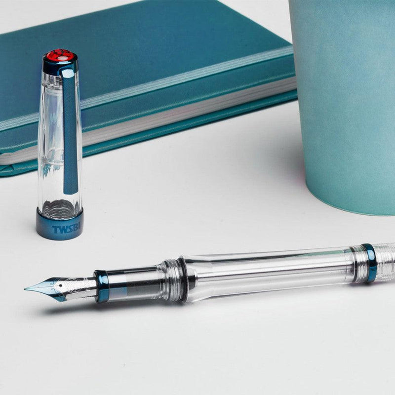 TWSBI VAC 700R Kyanite Fountain Pen - Pen With Nib Exposed With Notebook On Gray Background | EndlessPens